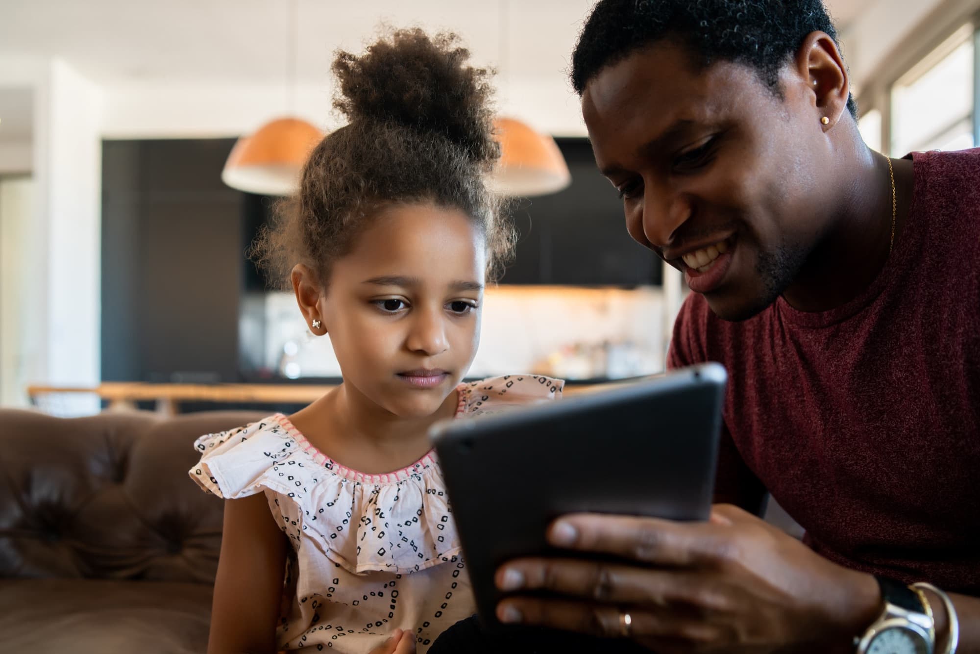 A father showing his daughter her school results on a tablet